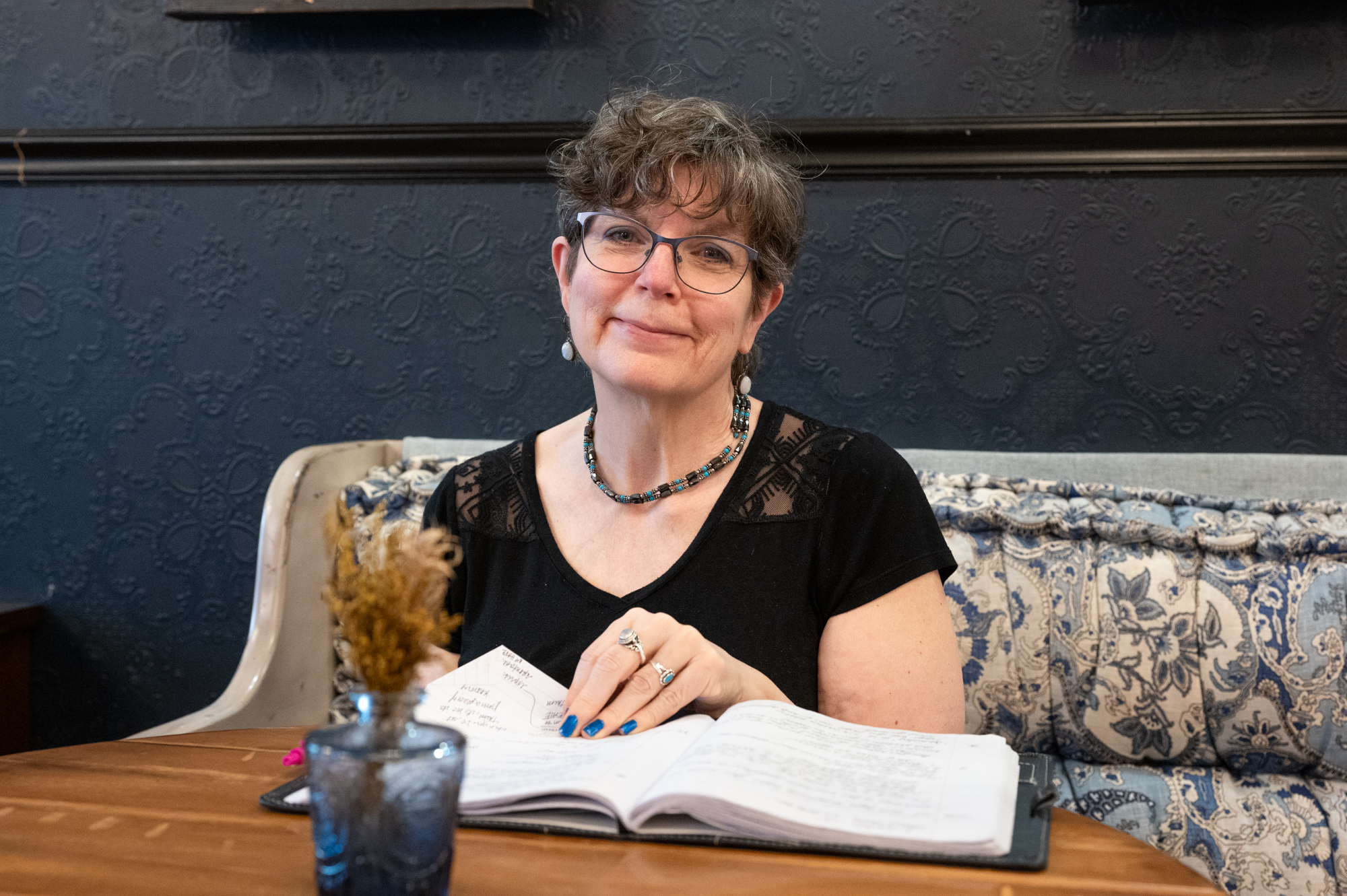 Barb Nangle looking up and smiling while flipping through a journal