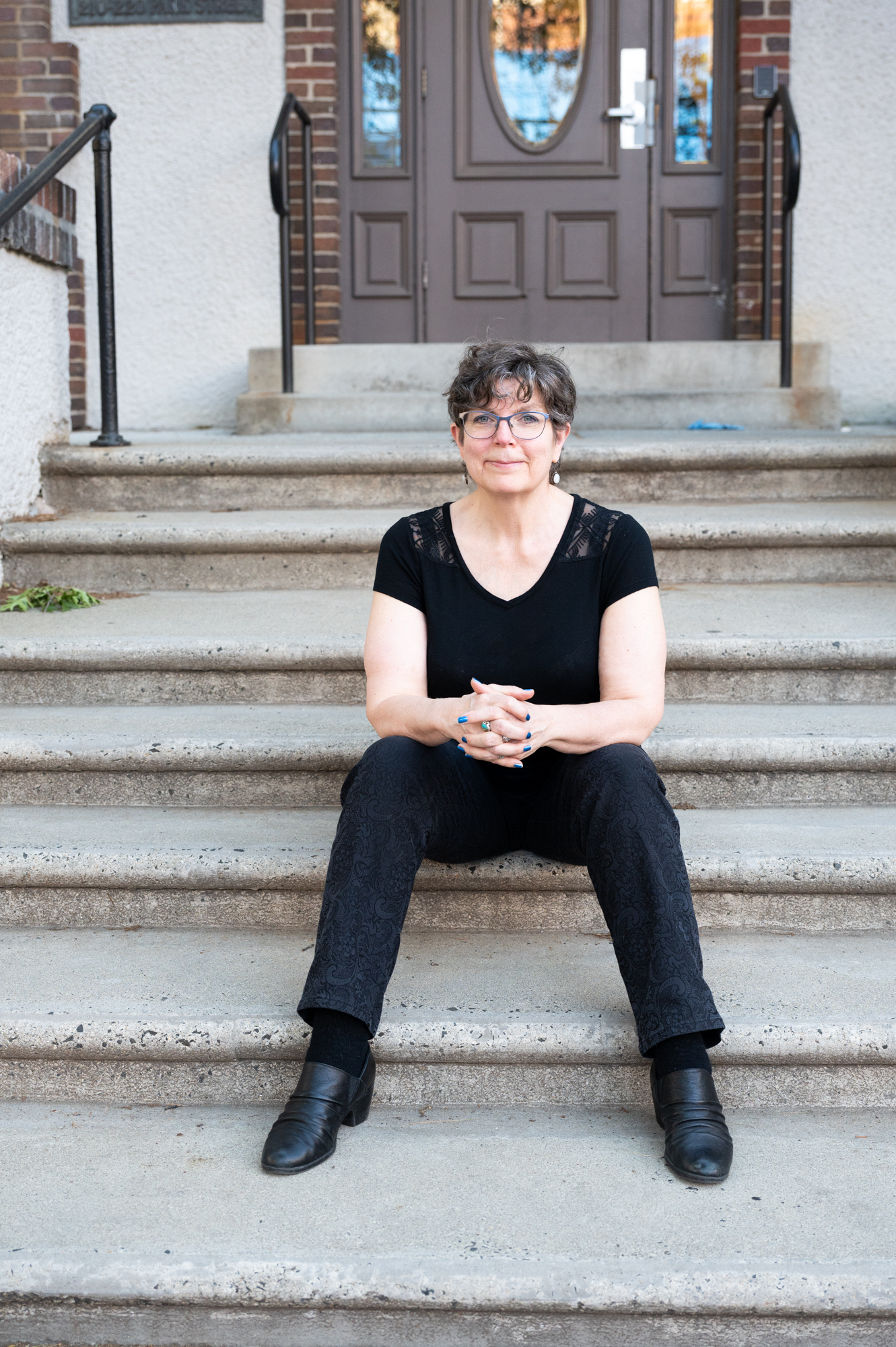 Barb Nangle seated confidently on apartment steps